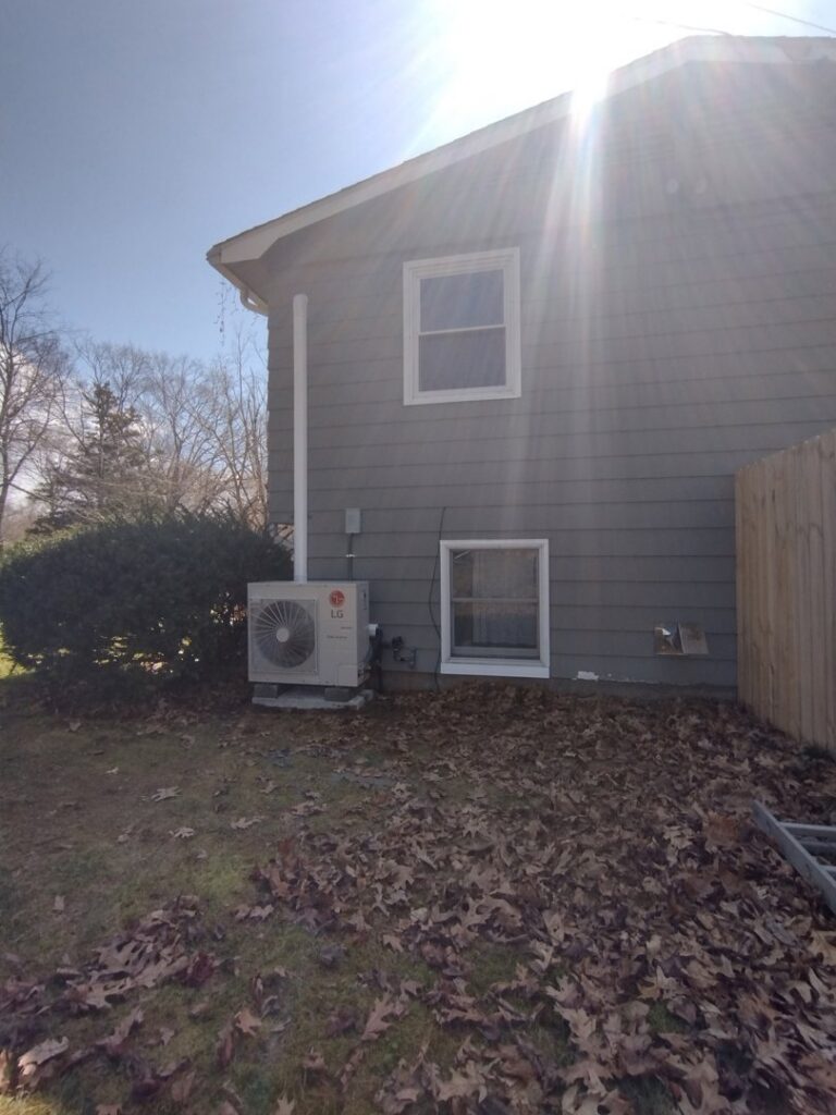 An outdoor HVAC unit, likely a heat pump or AC condenser, installed by CMAGS HVAC INC next to a home in Warwick, RI.
