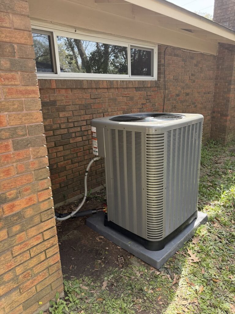 A newly installed outdoor HVAC condenser unit next to a brick home by Emergency Air in Chandler, AZ.