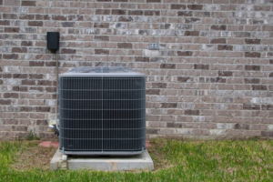 An outdoor HVAC unit installed next to a brick wall by Malone Heat & Air, Inc. in Chattanooga, TN