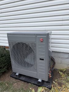 An outdoor HVAC unit, possibly a heat pump, installed next to a residential building by My HVAC Guy in North Canton, OH.