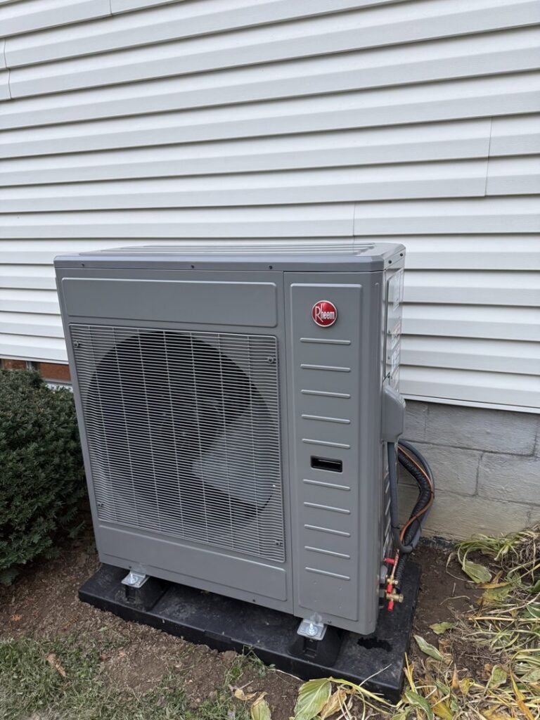 An outdoor HVAC unit, possibly a heat pump, installed next to a residential building by My HVAC Guy in North Canton, OH.