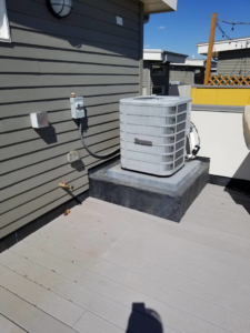 An outdoor HVAC unit installed on a deck next to a building by Western Sheet Metal Works Inc. in Aurora, CO.
