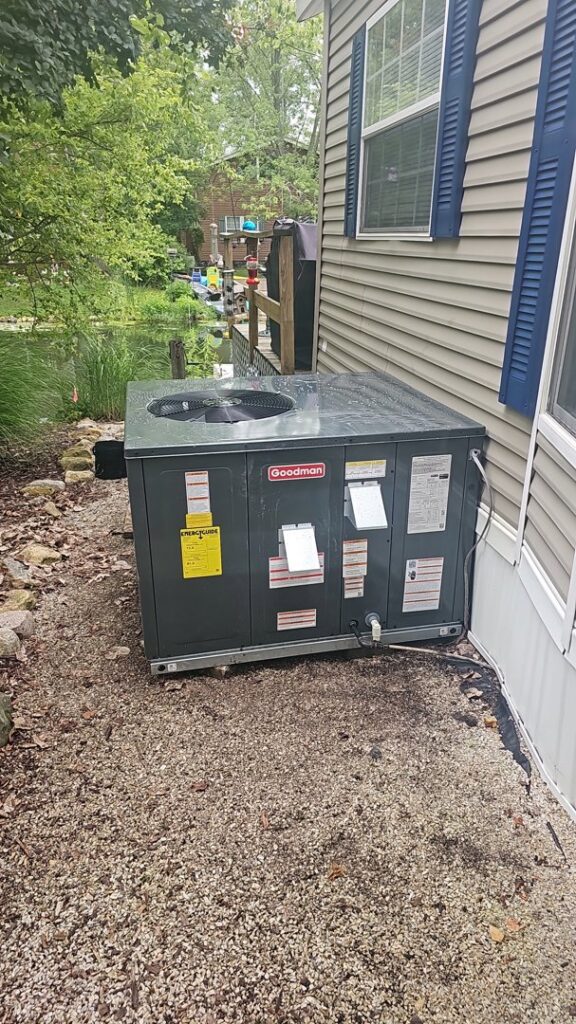 An outdoor HVAC unit installed next to a mobile home by DJ's Heating & Air Conditioning in Wilmington, IL.