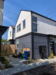 An outdoor HVAC unit installed next to a modern residential building by Progressive Comfort Solutions in Seattle, WA.