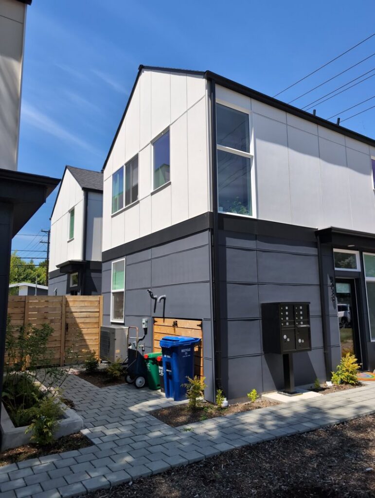 An outdoor HVAC unit installed next to a modern residential building by Progressive Comfort Solutions in Seattle, WA.