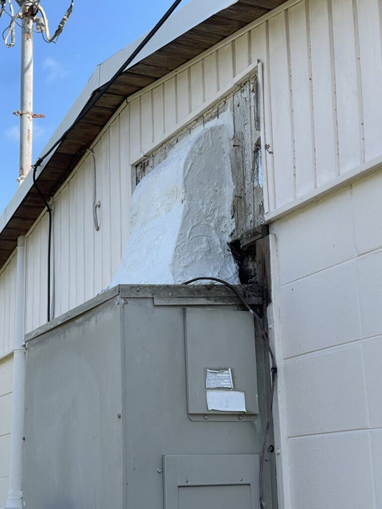 An outdoor HVAC unit with a poorly sealed connection to the building, a common issue addressed by Uplifting Air, LLC in San Antonio, FL.