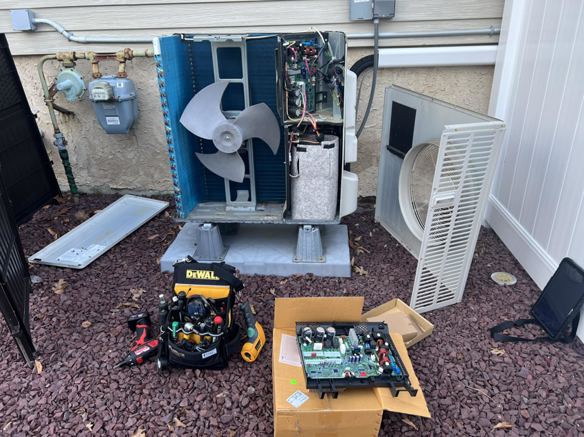 An outdoor HVAC condenser unit undergoing repair with tools and components visible at aghapy 1 in Jersey City, NJ