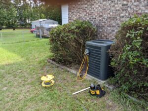 An outdoor HVAC unit being serviced with gauges connected by All American Heating and Air in Warner Robins, GA.