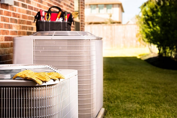 Outdoor HVAC condenser units with a tool bag and work gloves, ready for service by Infinity Heating & Cooling by Rivera in Kenosha, WI.
