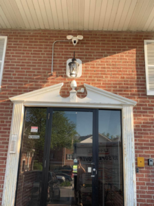 Outdoor lantern and security camera installation with visible conduit above a business entrance by Vera Electric in Aurora, IL.