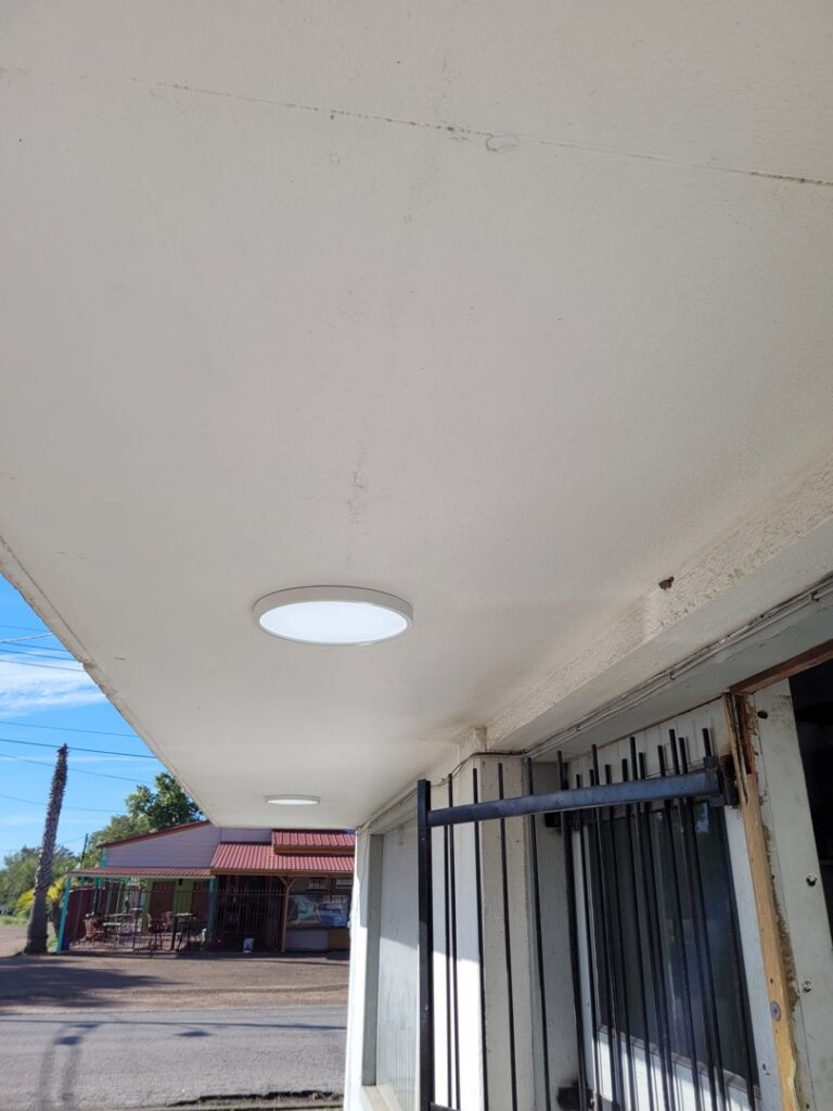 A new round LED light fixture installed on an outdoor ceiling by KS Retail Solutions in Victoria, TX