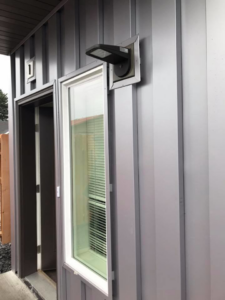 A newly installed modern outdoor light fixture on a building by Local Electric Inc. in Kodiak, AK