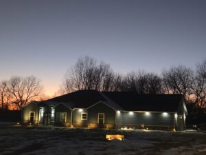 A house exterior at dusk illuminated by newly installed outdoor lighting by Warner Electric Service, LLC in Broken Arrow, OK.