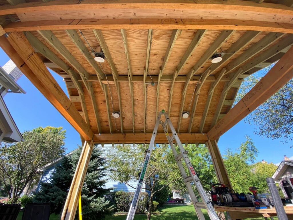 Outdoor lighting installation in progress under a wooden structure by Signature Electric INC. in Cleveland, OH