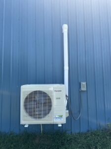 An outdoor Pioneer mini-split AC unit installed on a blue metal wall by Adam's Air Conditioning & Heating in Rockvale, TN