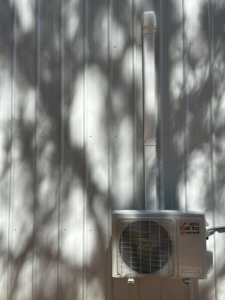 An outdoor mini-split AC unit installed on a corrugated wall by Spartan Air Conditioning in McIntosh, AL.