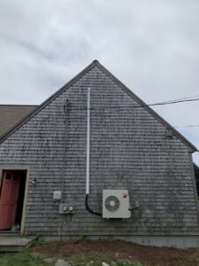 An outdoor mini-split condenser unit installed on a house by Atmos HVAC in Quincy, MA.