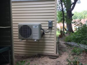 An outdoor mini-split condenser unit installed on the side of a building by Cool Tech Heating & Cooling in East Peoria, IL.