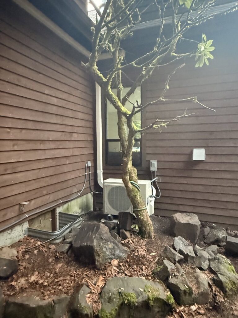 An outdoor ductless mini-split condenser unit installed next to a house by Cummings Inc. in Puyallup, WA.