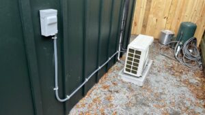An outdoor mini-split condenser unit professionally installed next to a building by Heads Heating & Air Conditioning in Theodore, AL.