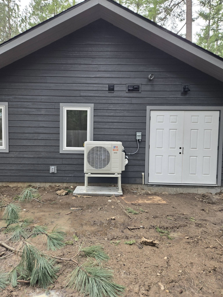 Outdoor mini-split condenser unit installed next to a building by Maddog Contracting LLC in Post Falls, ID.