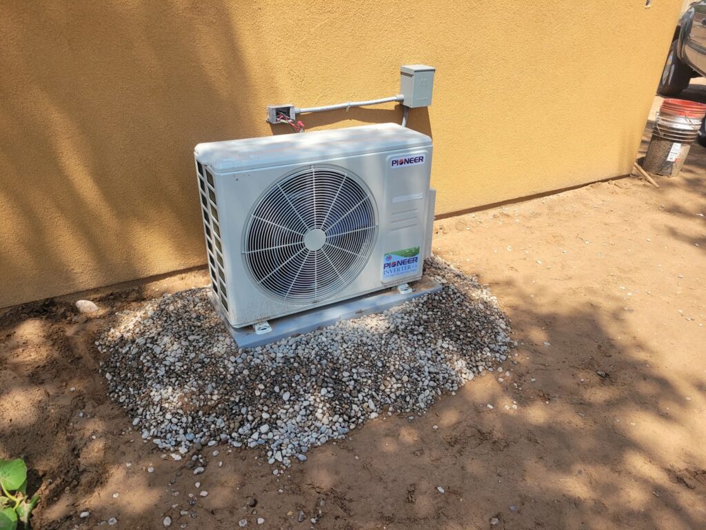 An outdoor mini-split condenser unit installed on a gravel bed by Pacheco Air Conditioning and Heating LLC in Albuquerque, NM.