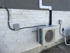 An outdoor mini-split condenser unit installed on a home's exterior wall by Simple Valley Heating and Cooling in Orem, UT