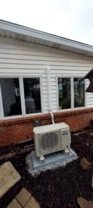 An outdoor mini-split condenser unit installed on the side of a house by Strine's Heating & A/C in York, PA.