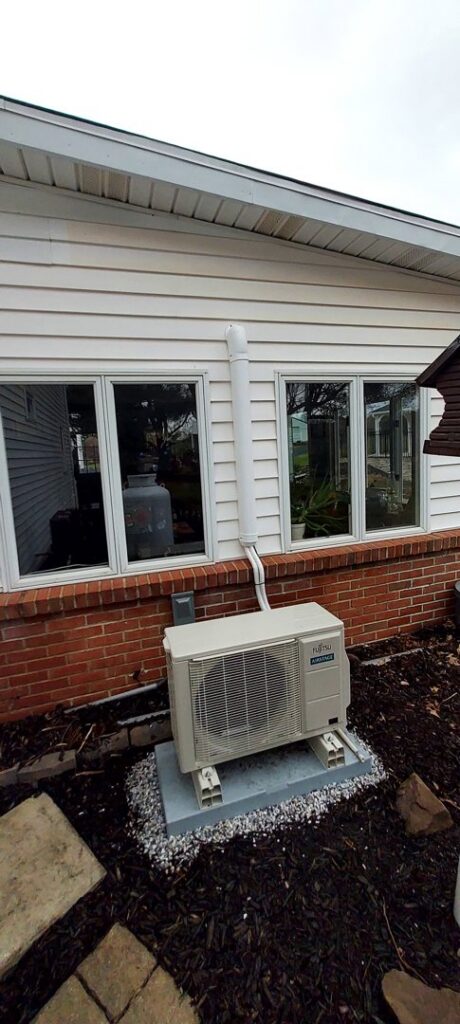 An outdoor mini-split condenser unit installed on the side of a house by Strine's Heating & A/C in York, PA.
