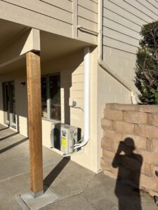 An outdoor mini-split condenser unit installed under a deck by Millard Heating & Cooling in Elkhorn, NE.