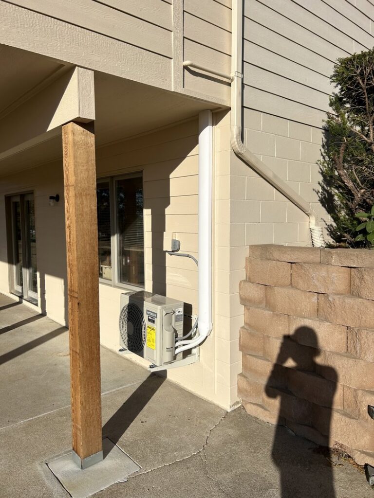 An outdoor mini-split condenser unit installed under a deck by Millard Heating & Cooling in Elkhorn, NE.