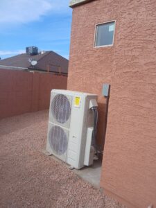 An outdoor mini-split condenser unit installed next to a building by BH cooling & Heating in Glendale, AZ.