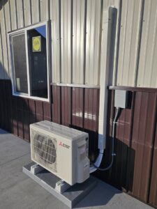An outdoor mini-split condenser unit installed next to a commercial building by ABC Mechanical Inc in Lawrenceville, GA.