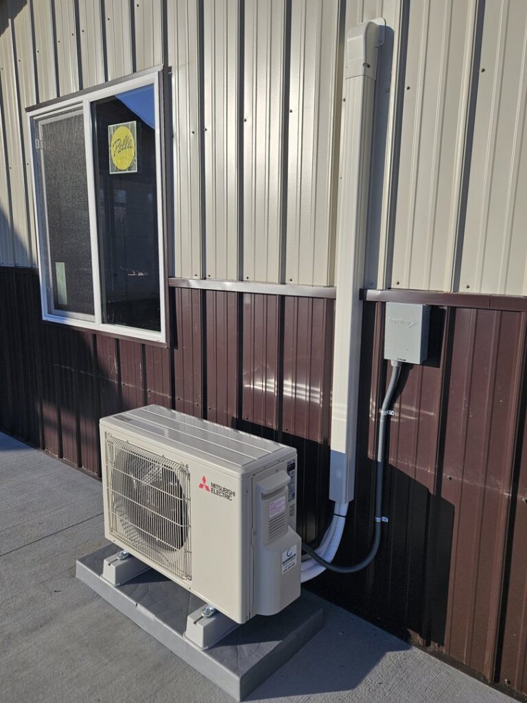 An outdoor mini-split condenser unit installed next to a commercial building by ABC Mechanical Inc in Lawrenceville, GA.