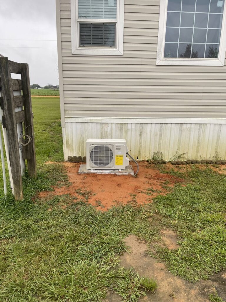 An outdoor mini-split condenser unit installed next to a mobile home by Circle L Heating and Cooling LLC in Atmore, AL.
