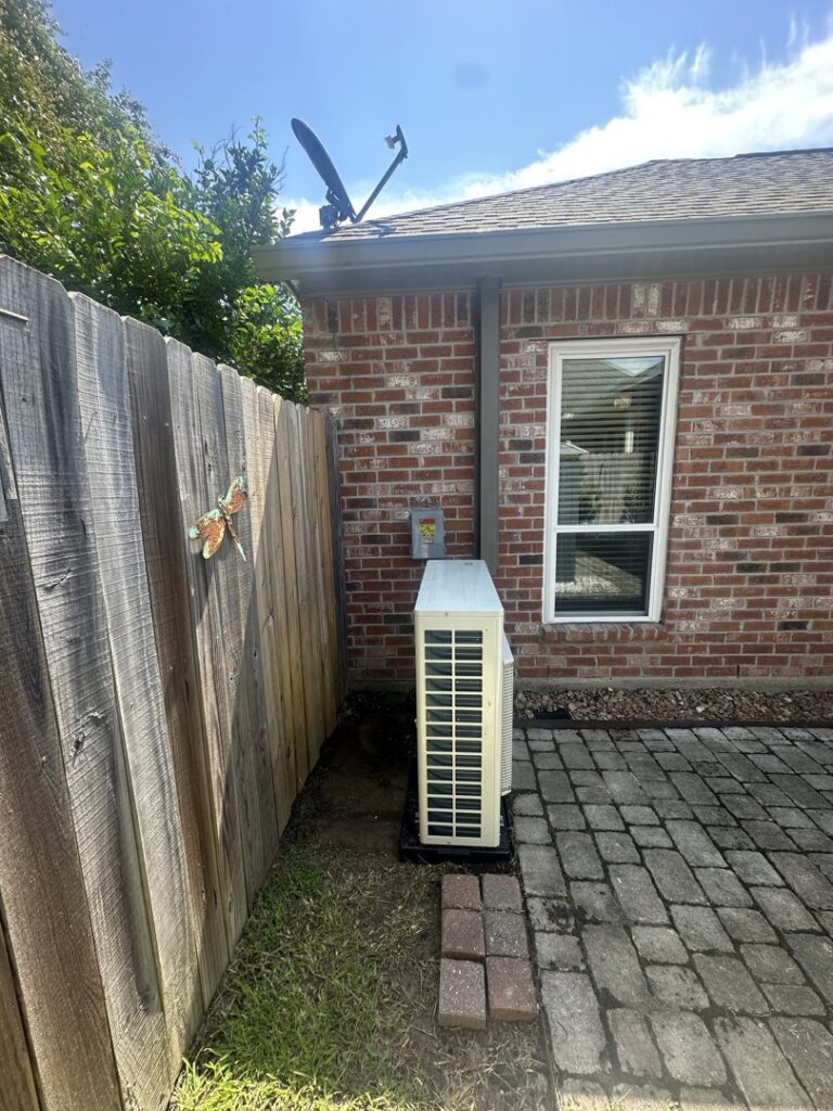 An outdoor mini-split condenser unit installed next to a residential building by Grand Slam Heating & Air in Baton Rouge, LA.
