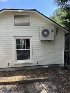 An outdoor mini-split condenser unit installed on the side of a building by AC Heating and Air Conditioning Services in Charleston, SC.
