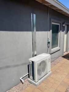 An outdoor mini-split condenser unit installed next to a house by Desert Heroes HVAC in Phoenix, AZ