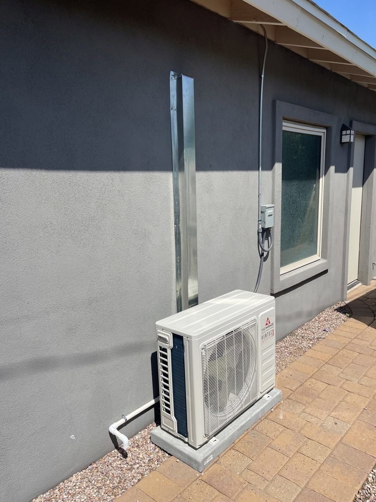 An outdoor mini-split condenser unit installed next to a house by Desert Heroes HVAC in Phoenix, AZ
