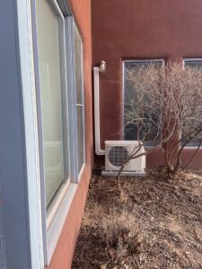 An outdoor mini-split condenser unit installed next to a building by Santa Fe Heating & Cooling LLC in Santa Fe, NM.