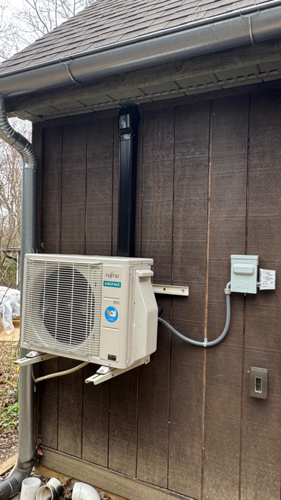 An outdoor Fujitsu Airstage mini-split condenser unit installed on the side of a building by Vai Services in Wilmington, DE.