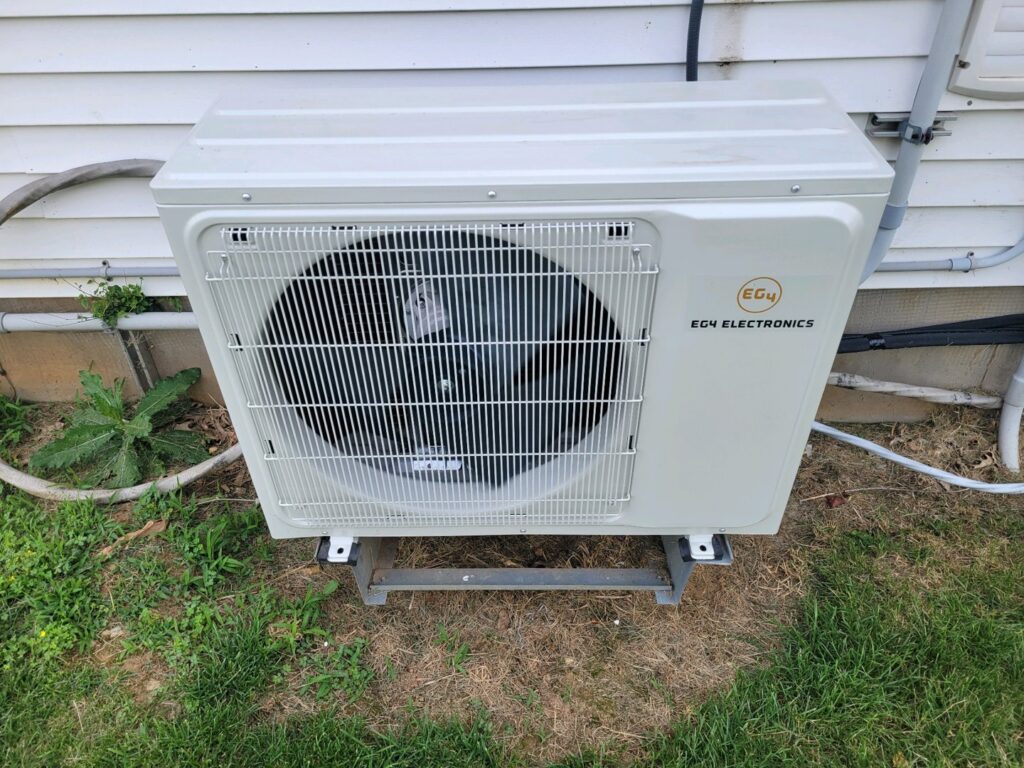 An outdoor mini-split condenser unit installed on a wall, serviced by JJJ Techs Heating and Cooling in Kinzers, PA.