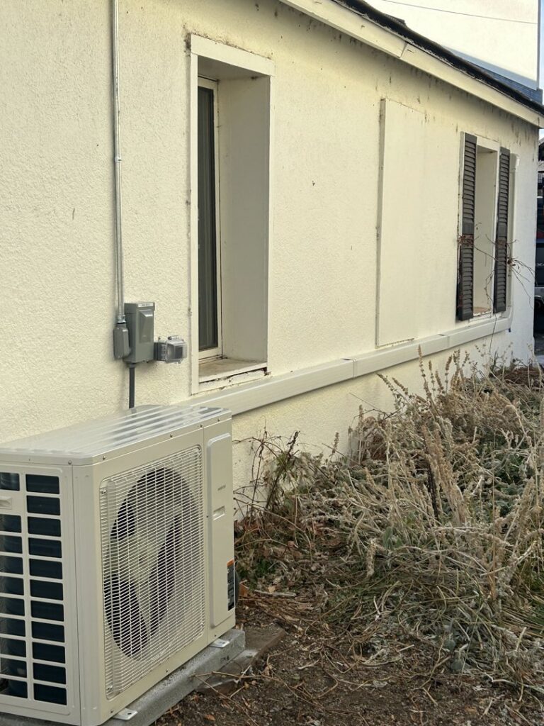 An outdoor mini-split condenser unit installed next to a building by R&R Mechanical Services in Greeley, CO.