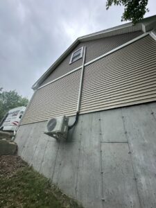 An outdoor mini-split condenser unit mounted on a wall bracket by Revolution HVAC in Owings Mills, MD.