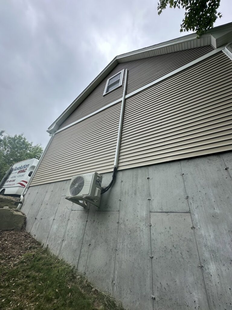 An outdoor mini-split condenser unit mounted on a wall bracket by Revolution HVAC in Owings Mills, MD.
