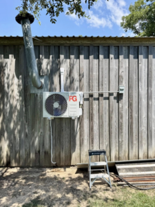 An outdoor mini-split condenser unit installed on a wooden wall by HD Precision Works in Iota, LA.