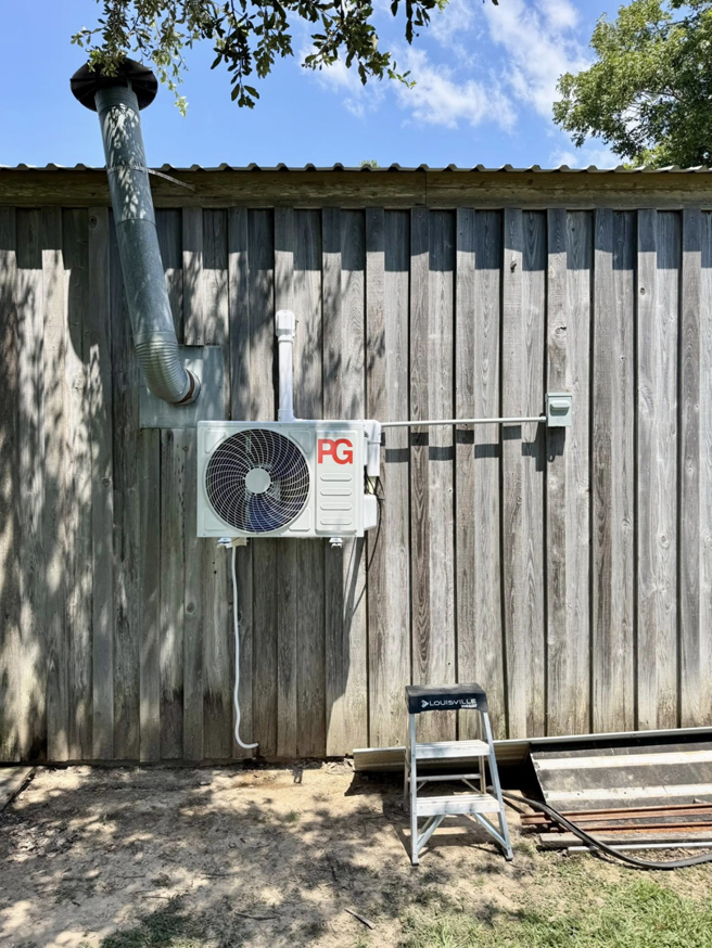 An outdoor mini-split condenser unit installed on a wooden wall by HD Precision Works in Iota, LA.