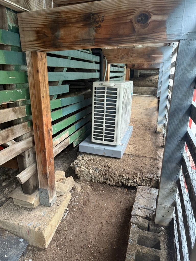 An outdoor mini-split HVAC unit installed under a deck by Air Masters, Inc. in Port Orchard, WA.