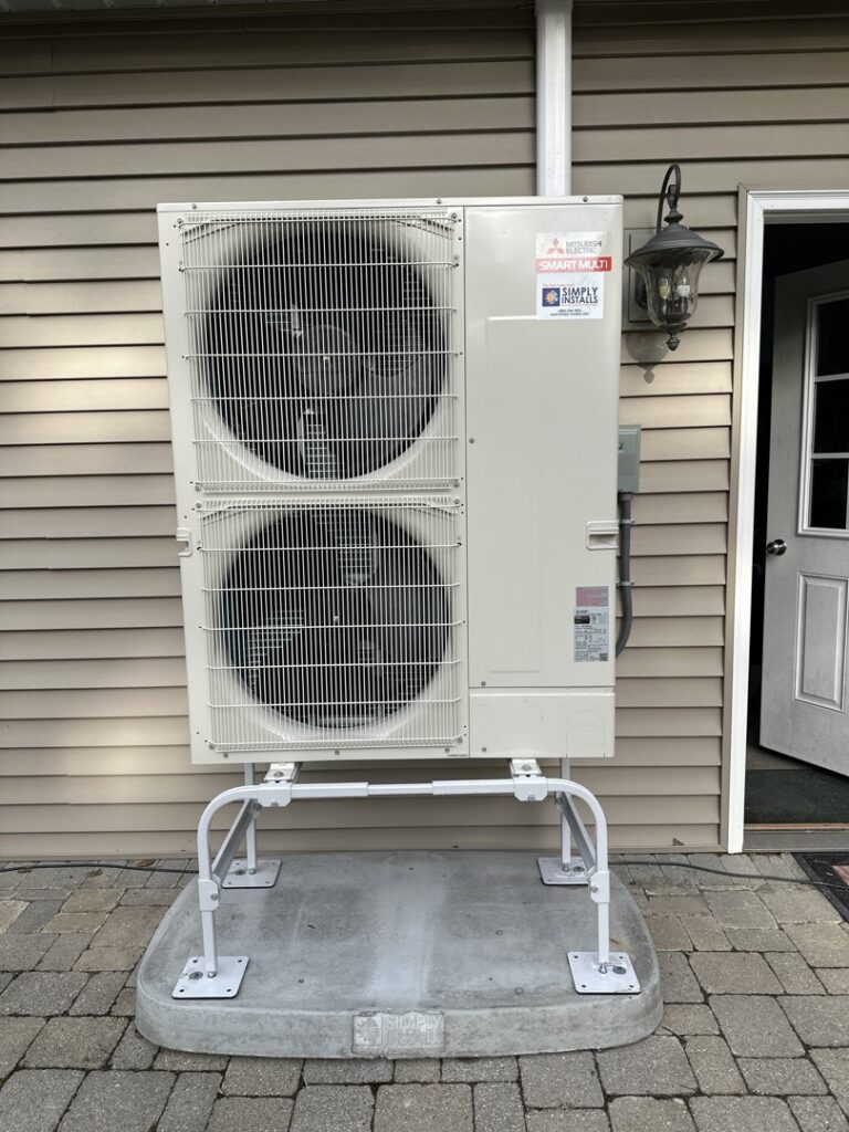An outdoor Mitsubishi Electric Smart Multi HVAC unit installed next to a residential building by Simply Installs Heating & Air Conditioning in Shortsville, NY.