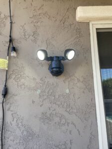 Installation of an outdoor motion-sensor floodlight on a stucco wall by Rogers Family Handyman in Chandler, AZ
